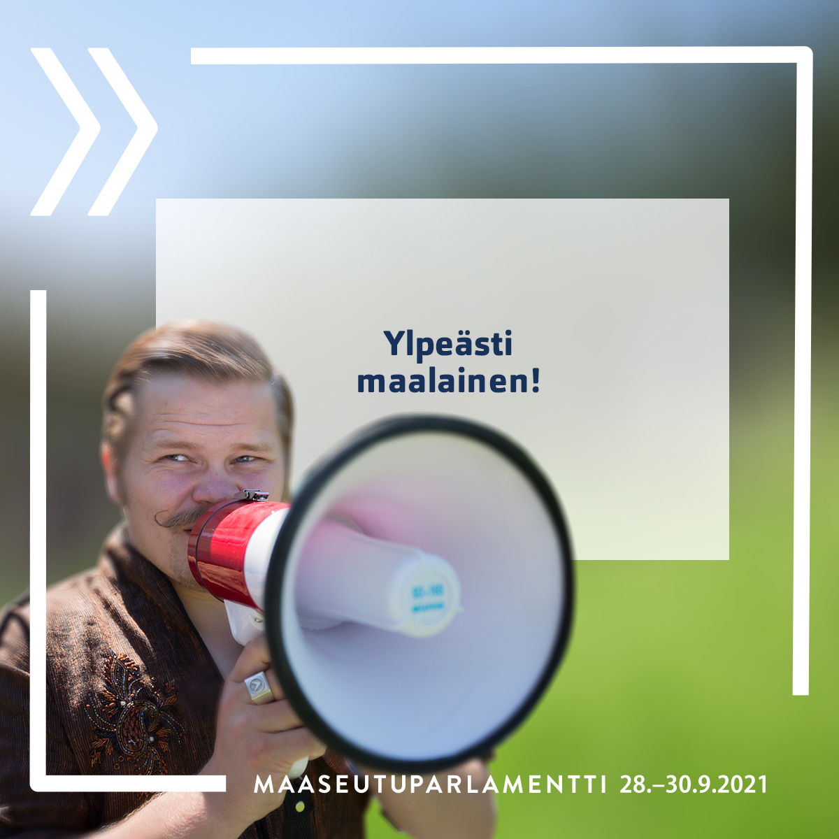 "Henkilö puhuu megafoniin, päällä tekstinä Ylpeästi maalainen"